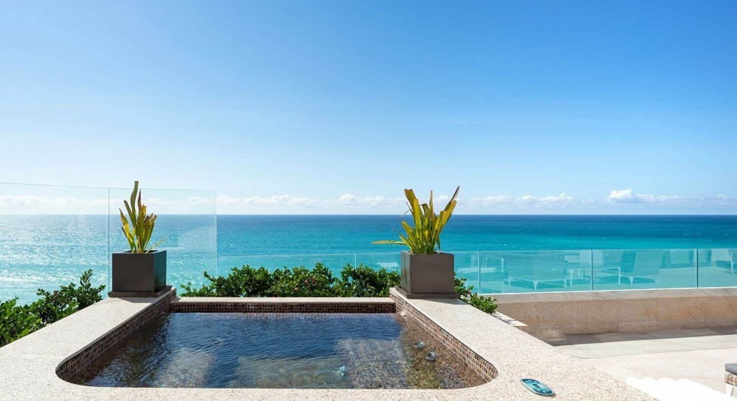 A balcony with a jacuzzi and sweeping turquoise ocean views.