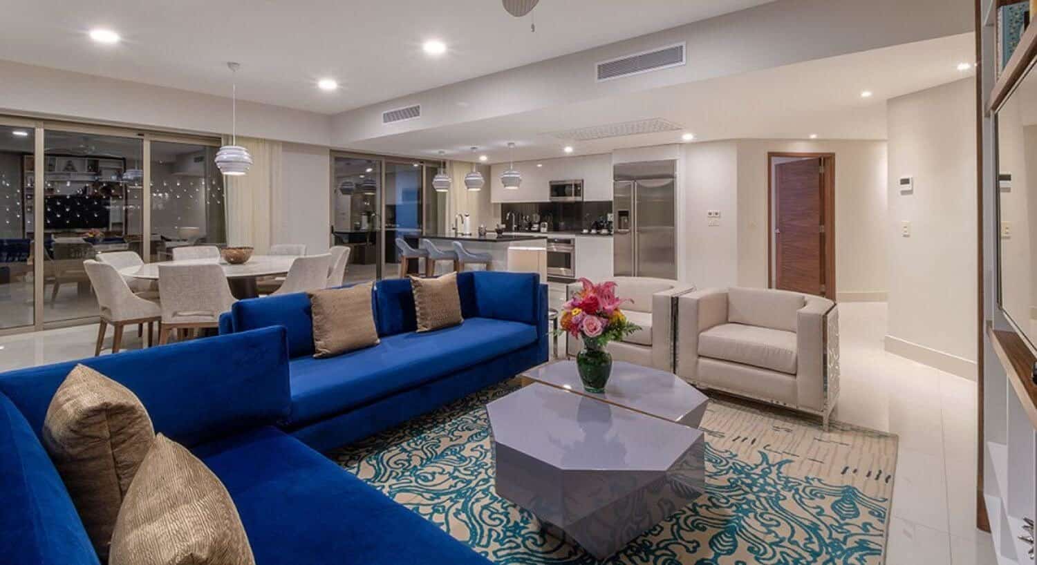 An open floor plan living room, dining are with a table and 8 chairs, and a gourmet kitchen, with sliding doors that lead out to a private balcony.