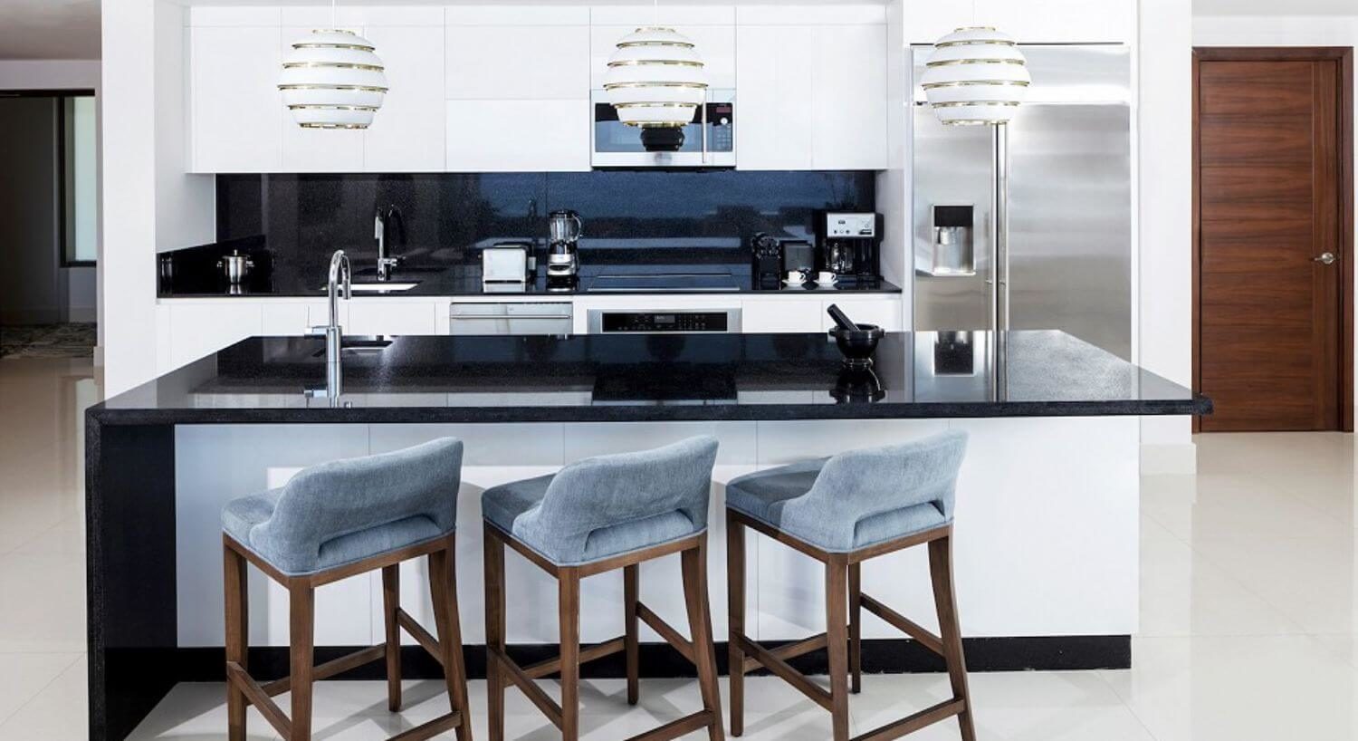 A gourmet kitchen with stainless steel appliance, sleek countertops, a breakfast bar, and bar stools.