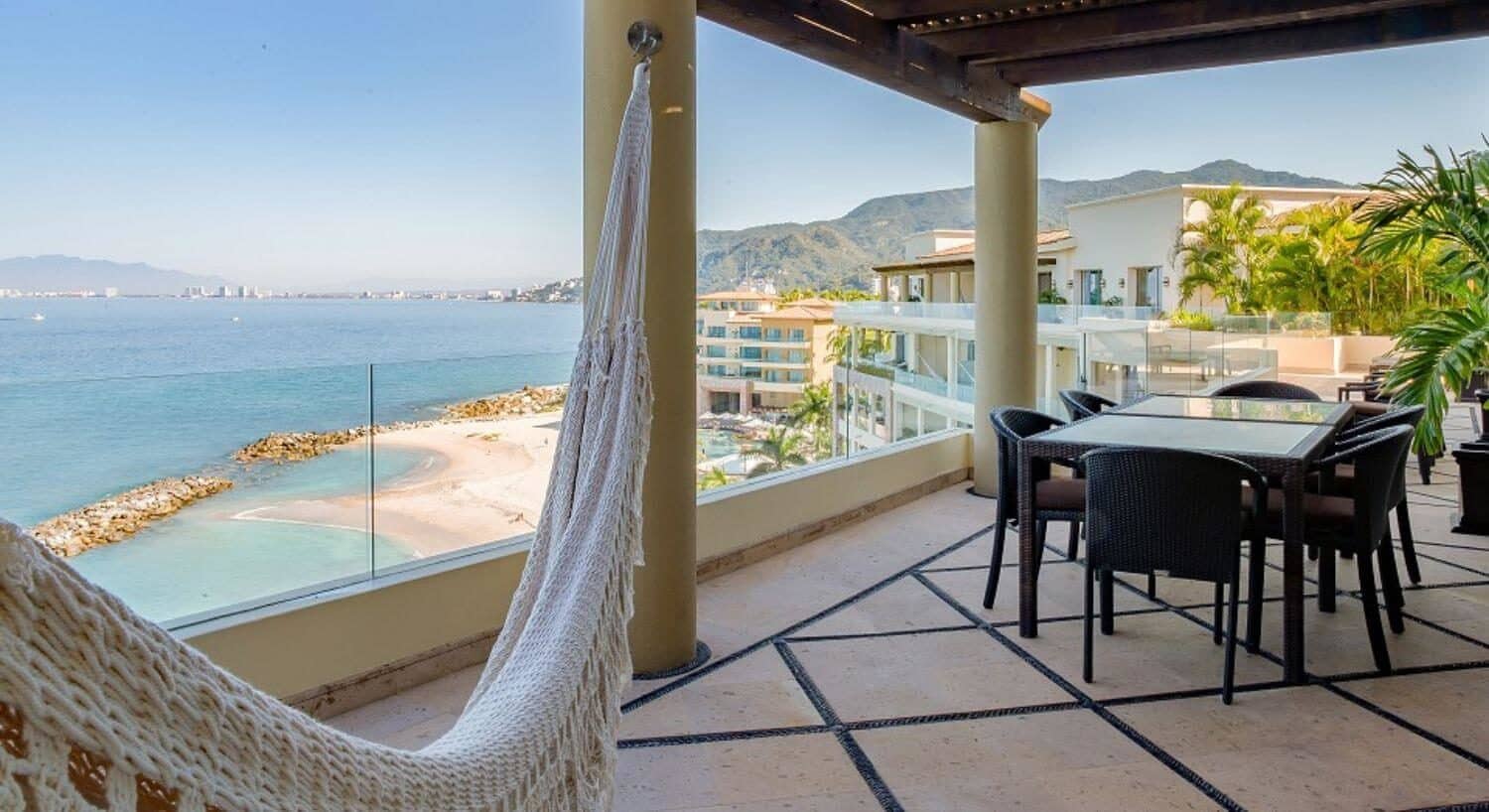 A private outdoor terrace with a dining table and chairs, and a hammock facing the ocean and mountains of Banderas Bay.
