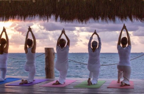 People doing yoga on a pier overlooking the ocean.