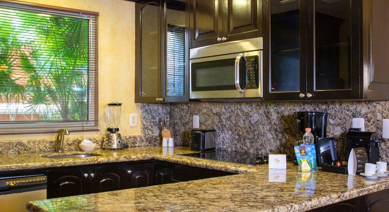A U-shaped kitchen with granite countertops, dark brown cupboards, and stainless steel appliances.