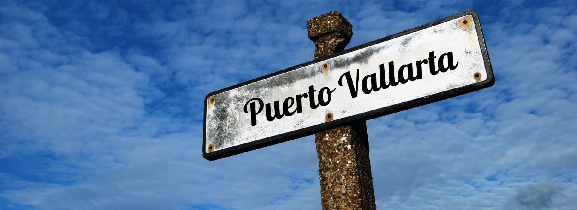 a white aged sign on an old stone pole that says Puerto Vallarta