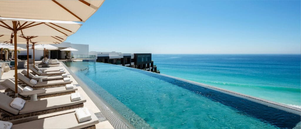 A rooftop pool with turqoise ocean views and lounge chairs with shade umbrellas