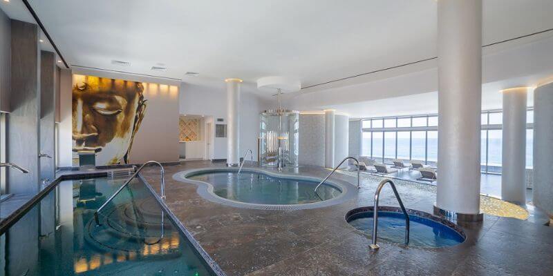 a series of various size pools in a spa with lounge chairs facing the ocean