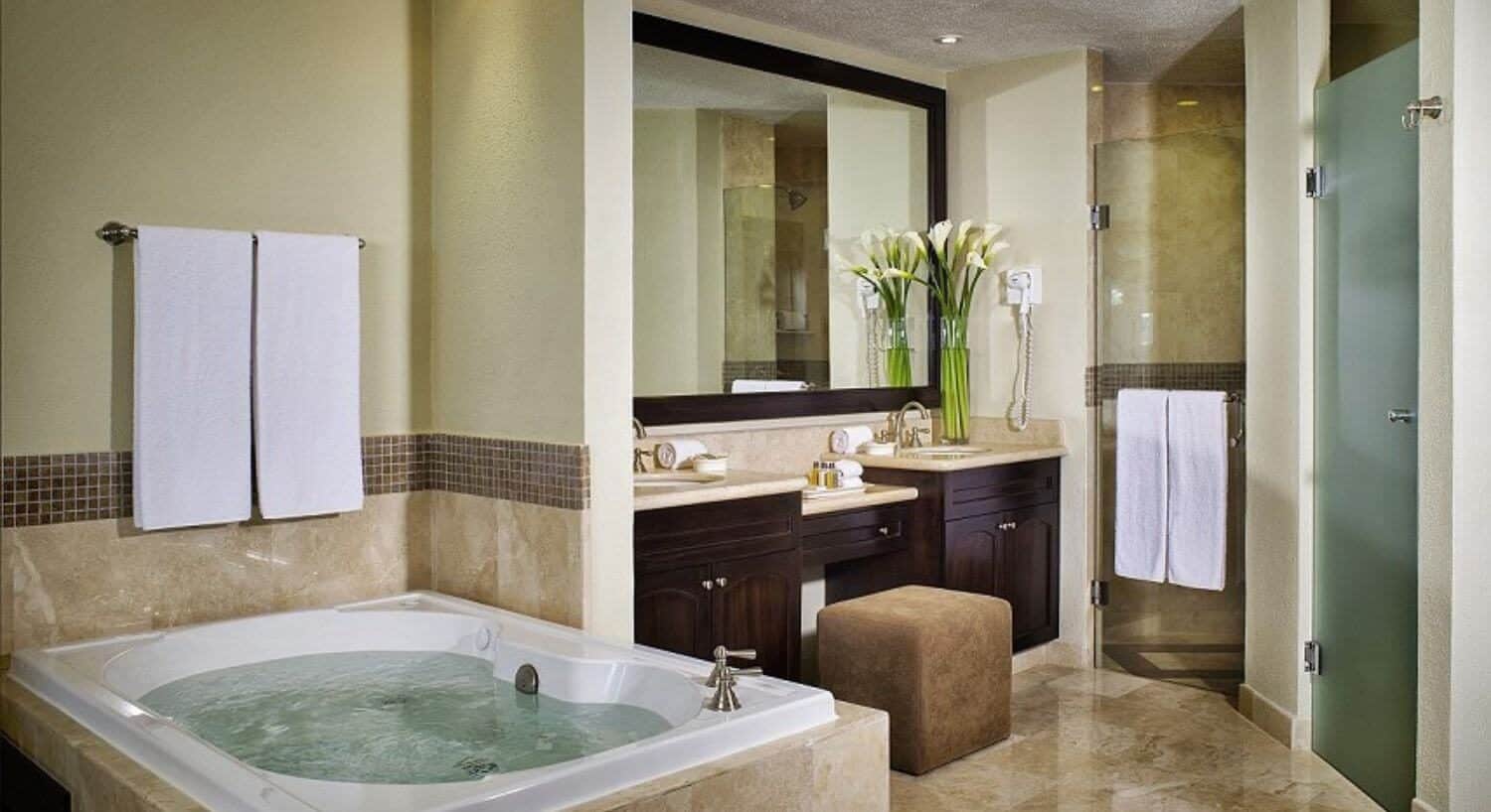 A bathroom with a jacuzzi tub, double sink vanities, and a shower.